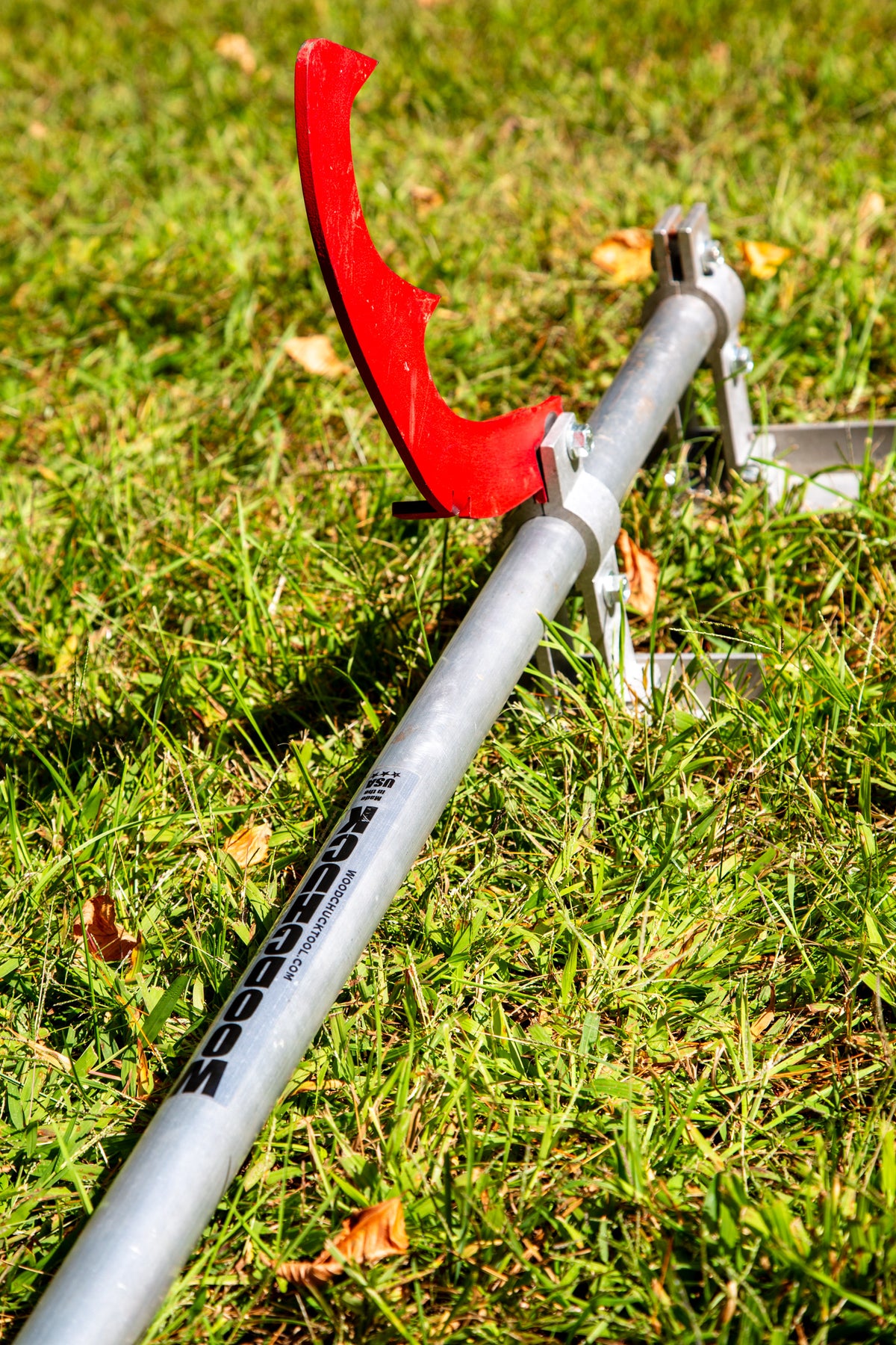 Timberjack lying on grass with its red hook raised and the Woodchuck sticker on the aluminum handle